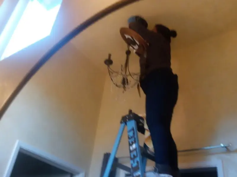 Electrician installing a chandelier in a Hilltown residence